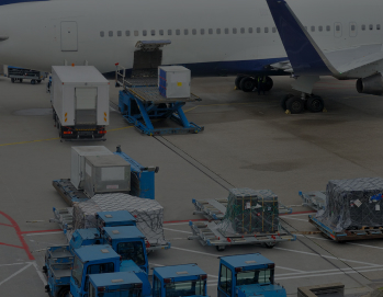 видны тележки с грузом, подъемник и грузовой автомобиль, идущие к открытому грузовому отсеку