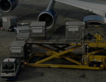 Вид на грузовые контейнеры, размещенные на платформе возле самолета, с турбинами Boeing на заднем плане.